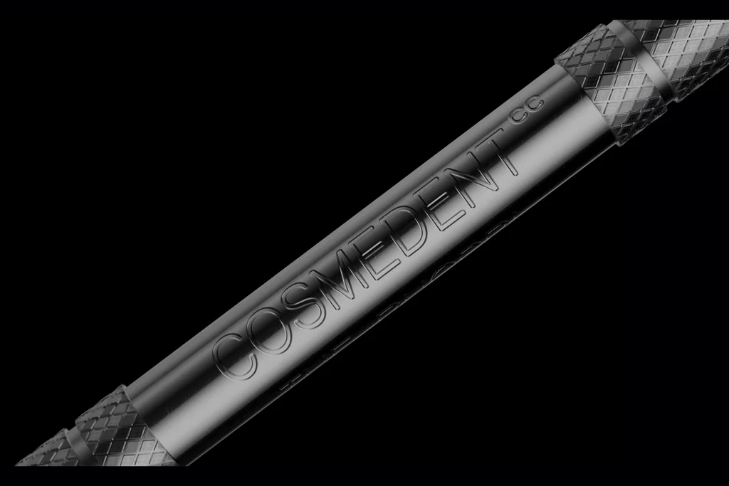Close-up CGI of a dental instrument handle with a knurled grip and engraved brand name on a black background