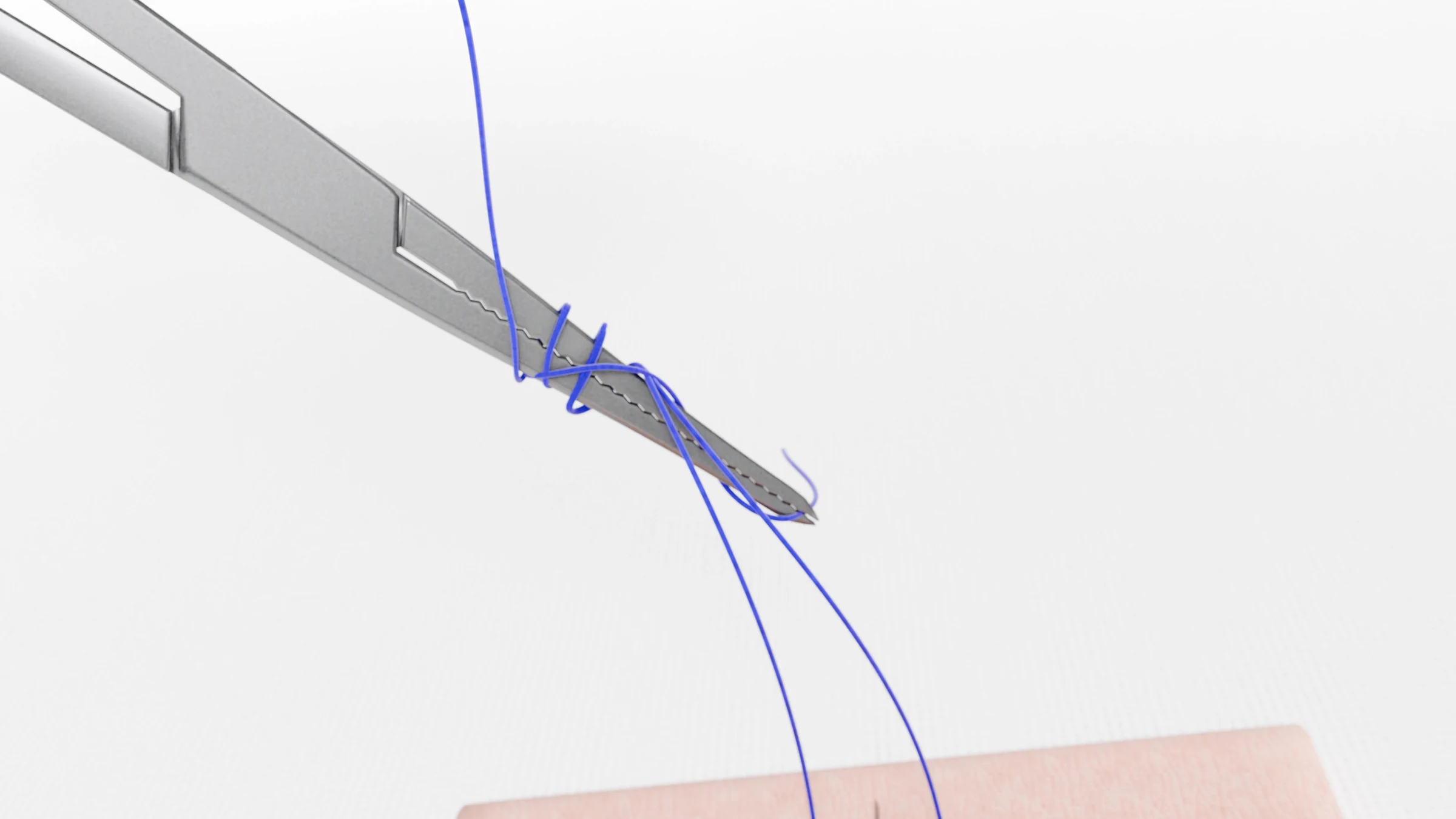 Loops of suture on the needle driver above the practice pad as the knot begins to form