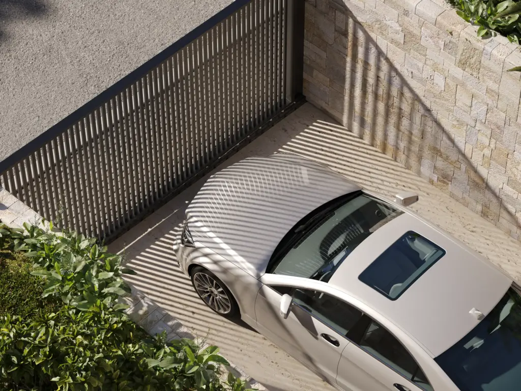 Aerial view of modern driveway with parked car and vertical metal gate shadows