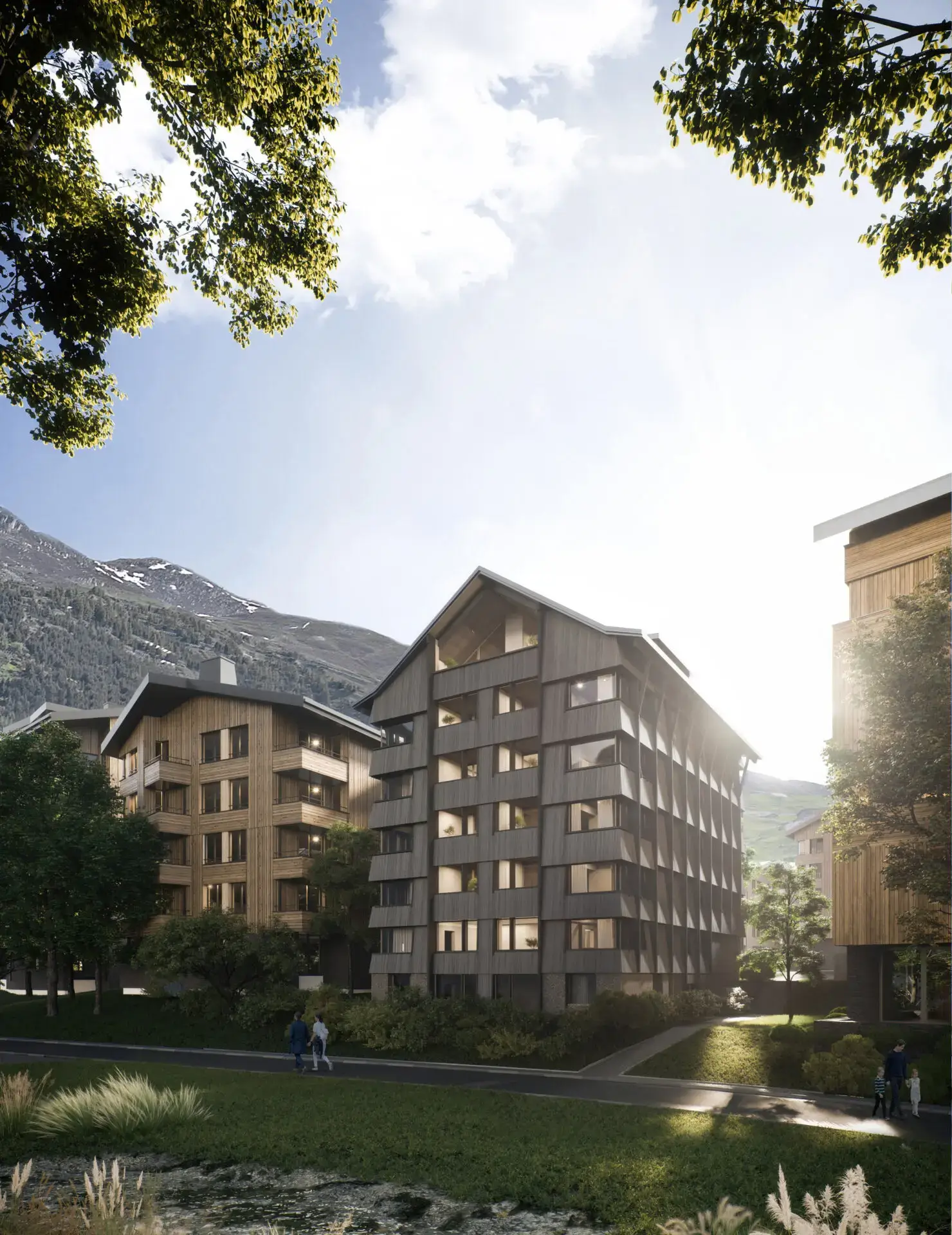 Mid-rise residential buildings in an alpine village setting with wooden facades, greenery, and mountain backdrop