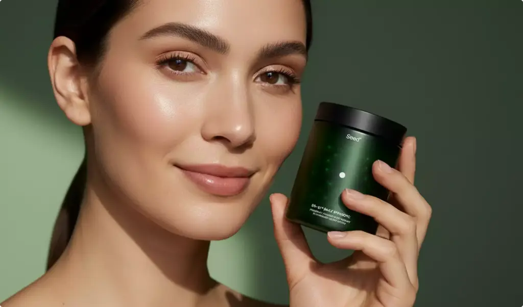 Woman holding green Seed jar near face against green background, supplement packaging design