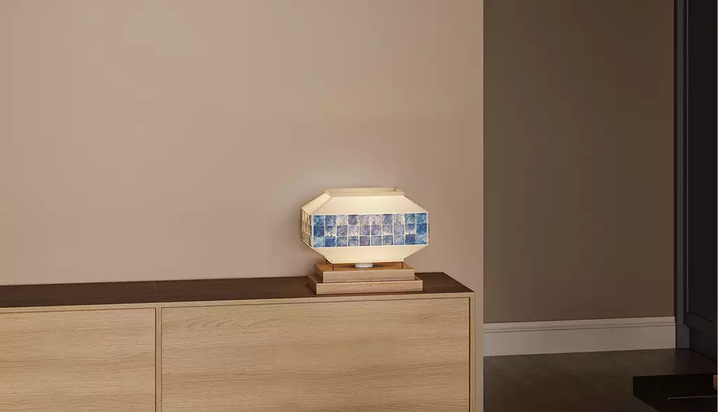 Geometric table lamp with blue tile band on wooden cabinet against beige wall for 3D product visualization