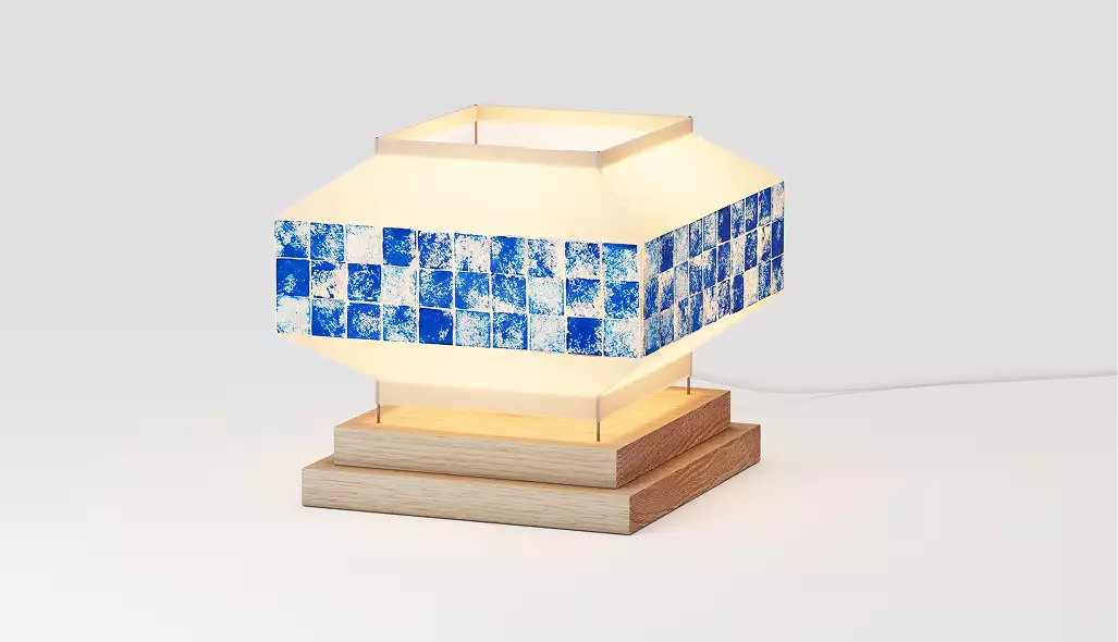 Geometric table lamp with blue tile band and wooden base glowing on neutral background for 3D product visualization