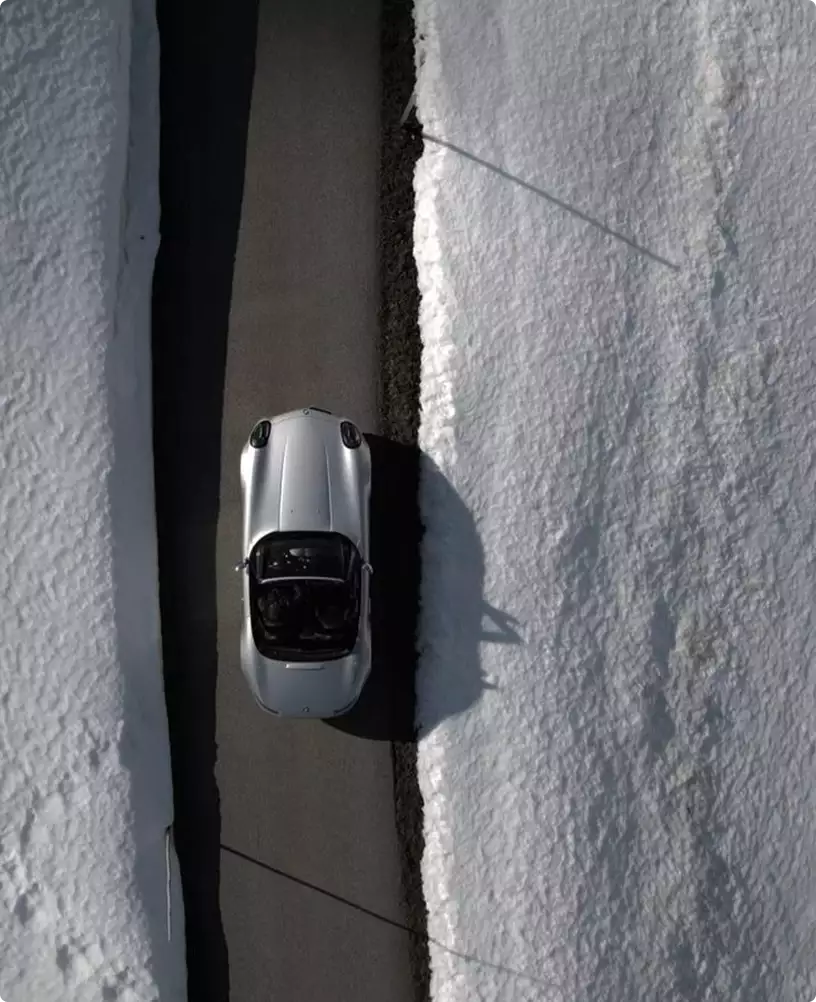 3D winter rendering of a silver car driving on a road between high snowbanks