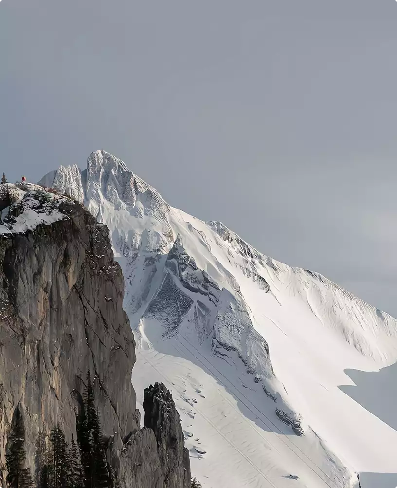 3D winter rendering of a snowy mountain peak with rocky cliffs under a pale sky