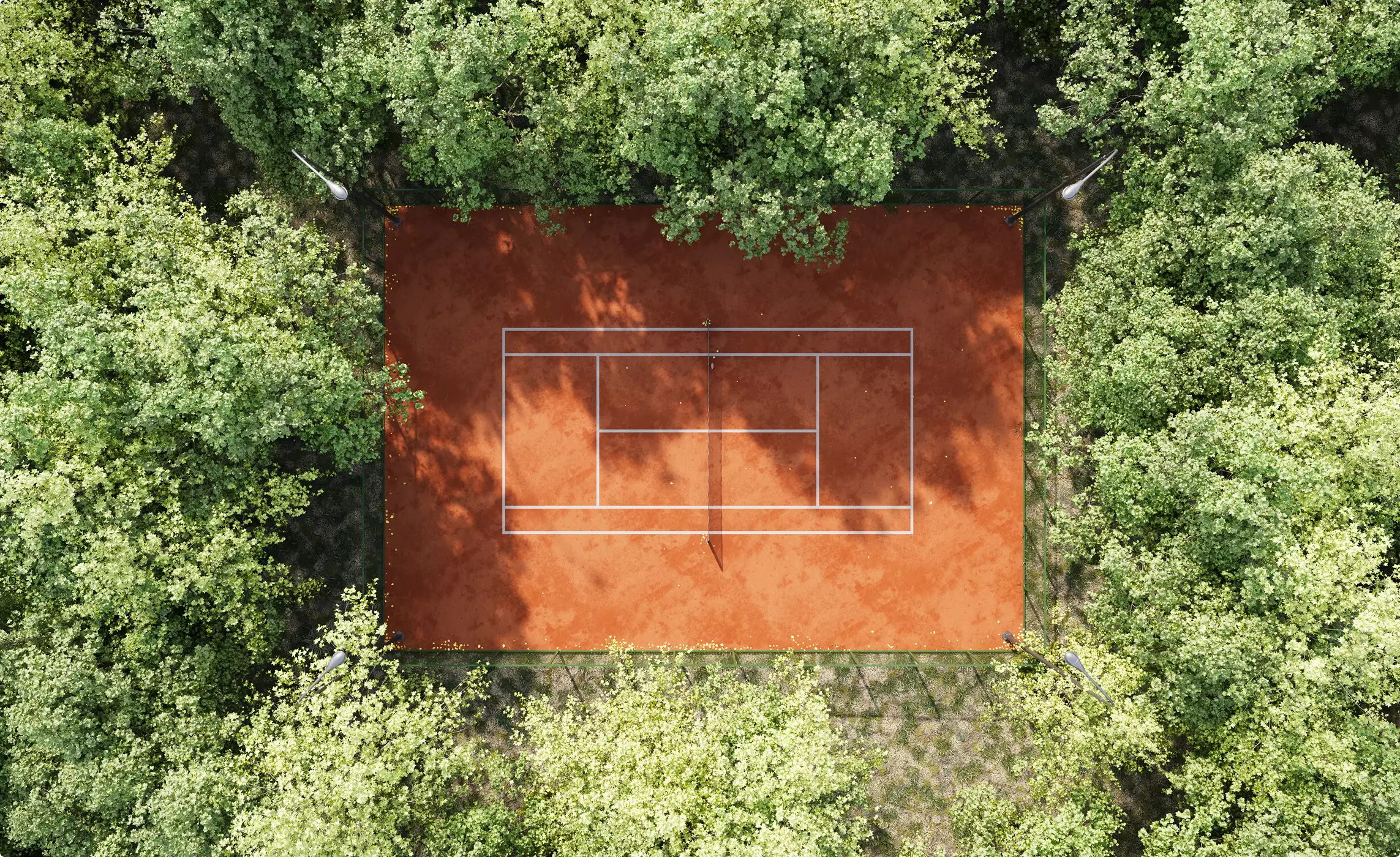 Aerial clay tennis court design surrounded by green forest trees and lighting poles
