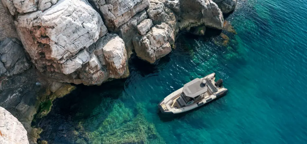 Boat 3d visualization of a motorboat beside rocky cliffs in clear turquoise water