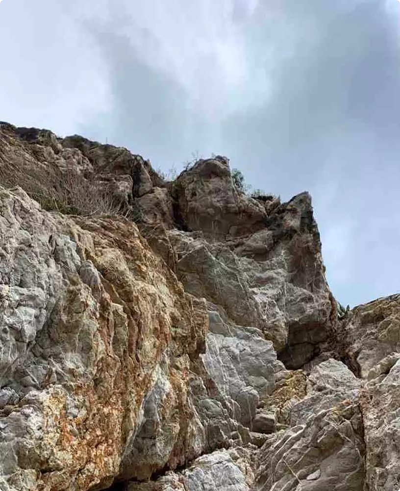 Boat rendering with rugged coastal rock cliffs rising under a pale sky.