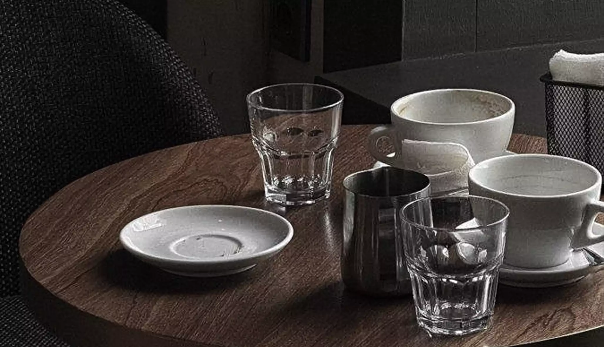 Round cafe table with cups and glasses in warm espresso product design setting