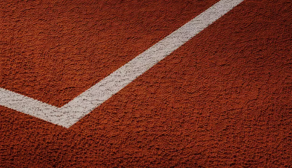 Clay tennis court design close-up highlighting textured red surface and white boundary lines