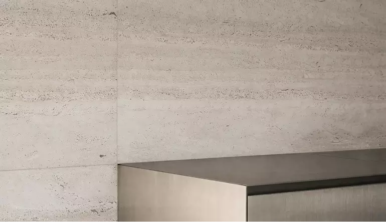 Stone wall detail in custom exhibition stand design with metal counter edge and neutral surface texture