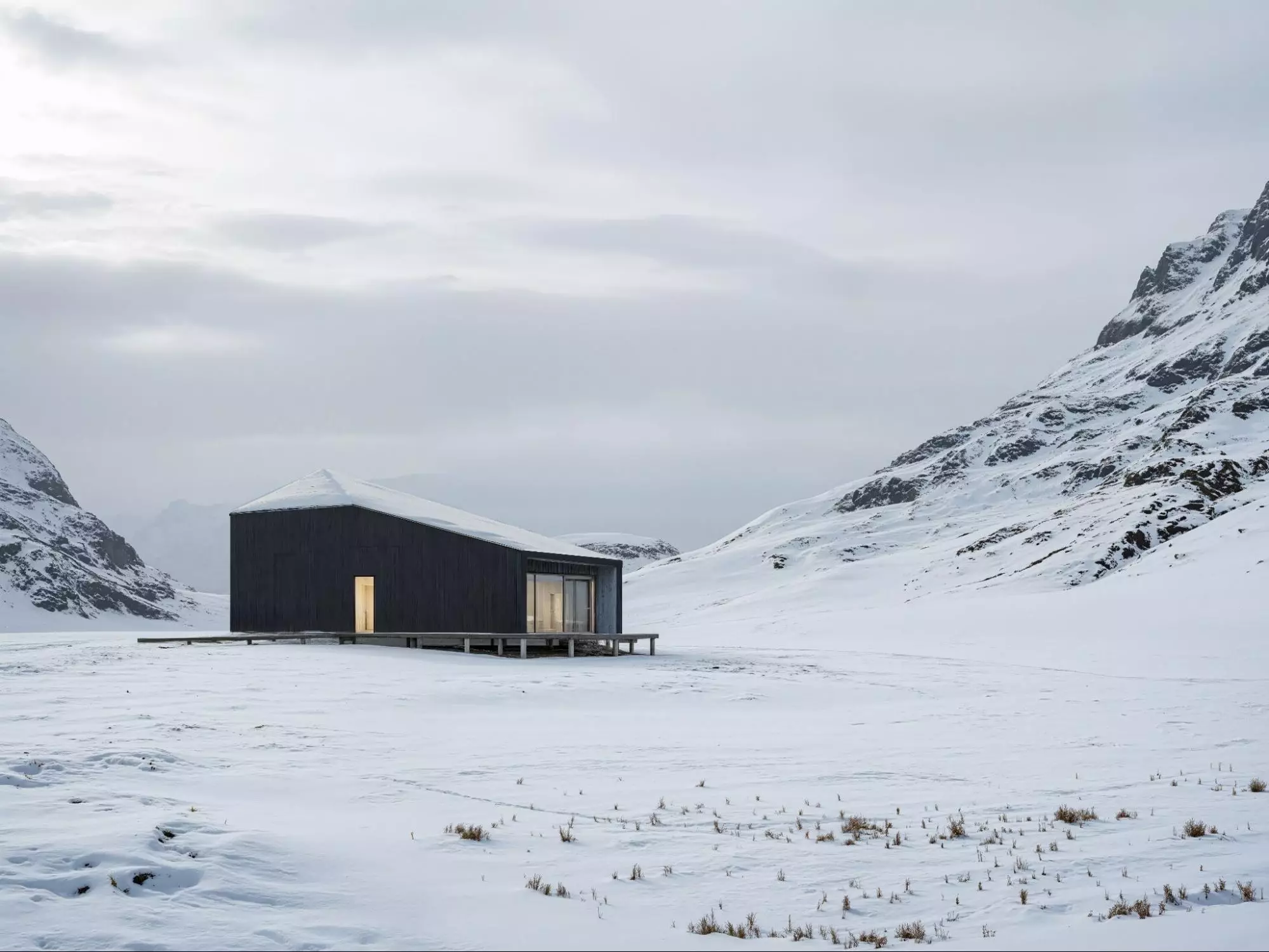 What Is Green Architecture? Meaning, Principles, and Examples Minimal dark cabin in a snowy mountain valley with glowing windows