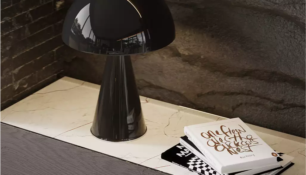 exterior rendering of modern table lamp on marble surface beside stacked books and textured stone wall