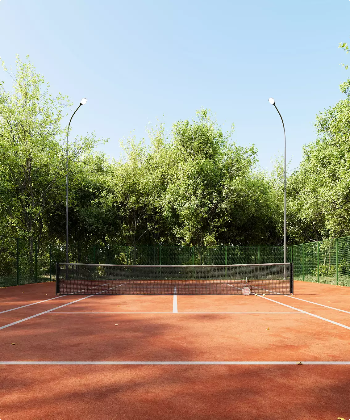 Clay tennis court design in forest with green fence, net, tall lights under blue sky.