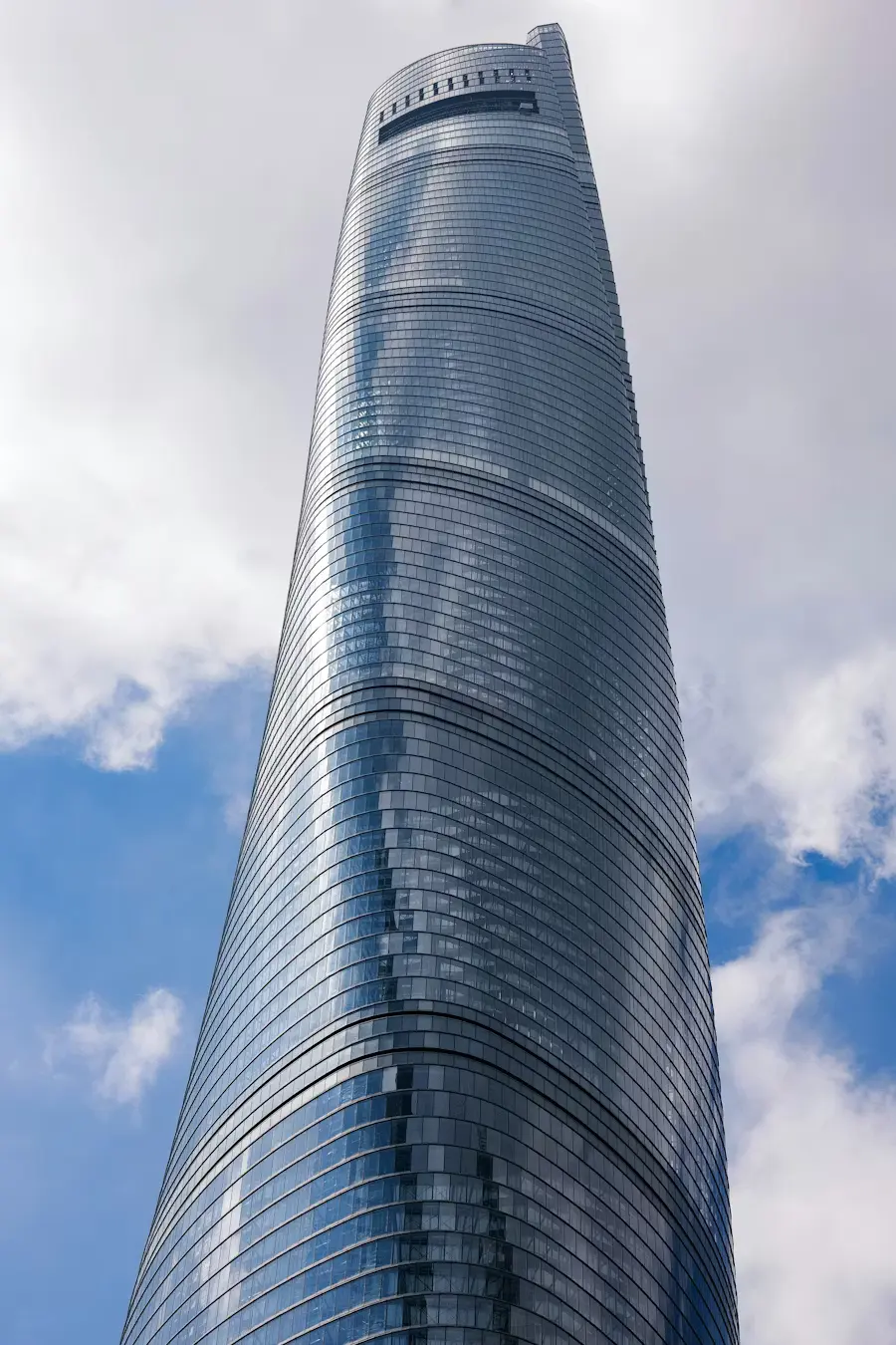 Green architecture glass skyscraper rising into clouds, green building in a dense urban skyline