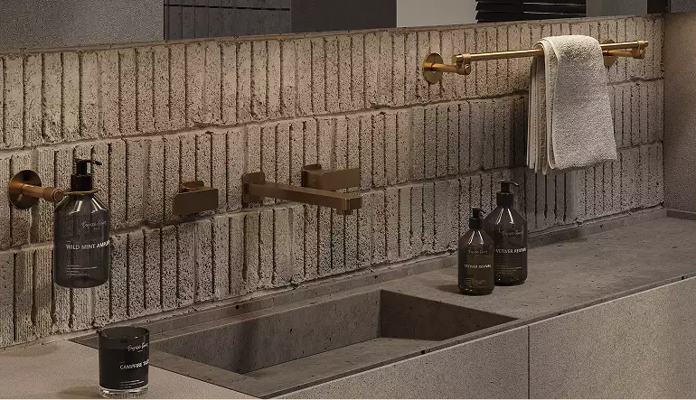 Interior modular homes bathroom sink with brick backsplash, brass rail, faucet, and bottles