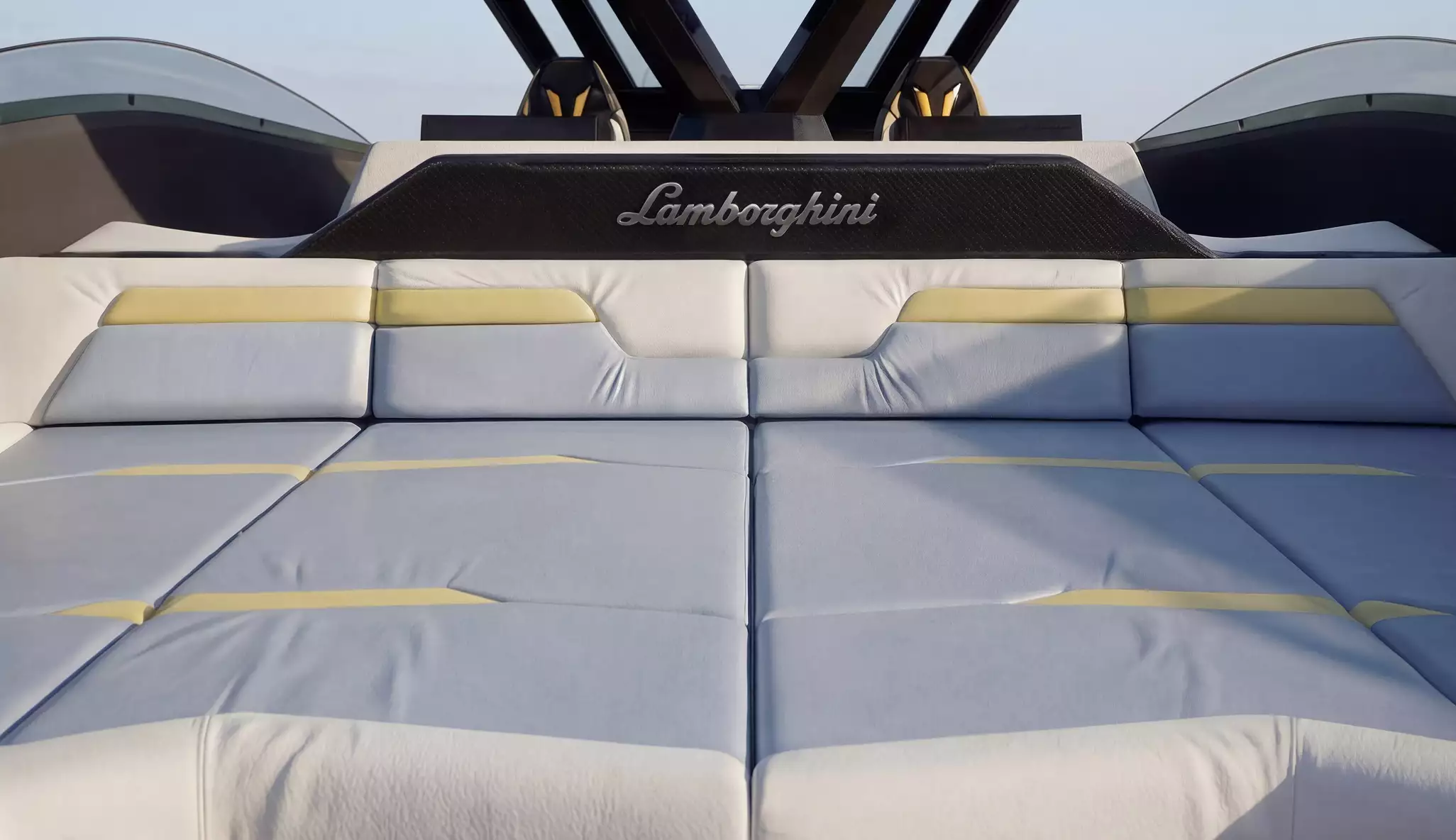 Yacht interior sunbed area with large cushioned lounge, subtle yellow accents, and open-air Lamborghini-inspired yacht design