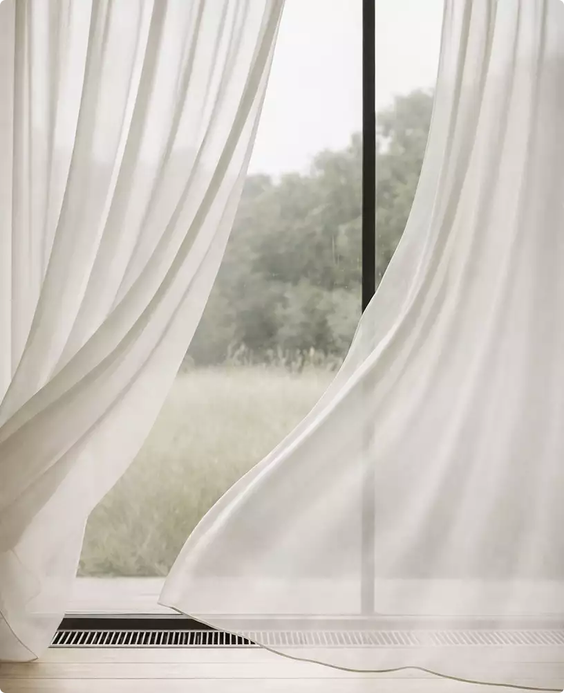 Robotic vacuum cleaner design cleaning floor near large window with flowing curtains in modern home interior