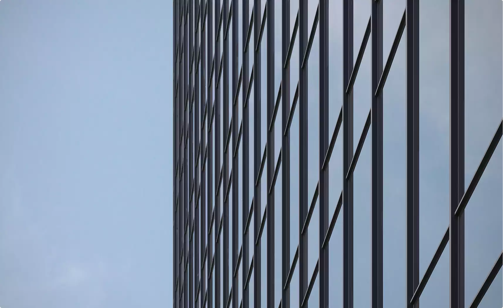 Facade edge skyscraper rendering with vertical dark mullions and reflective glass against a pale blue sky.