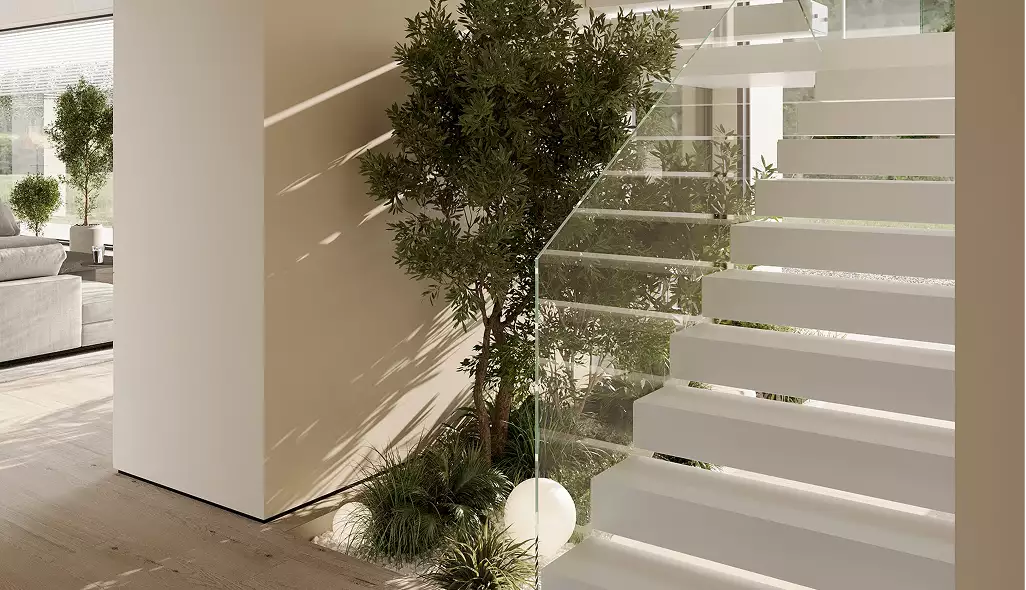Vacuum cleaner design concept sphere floor device beside indoor plants under modern staircase in sunlit home interior