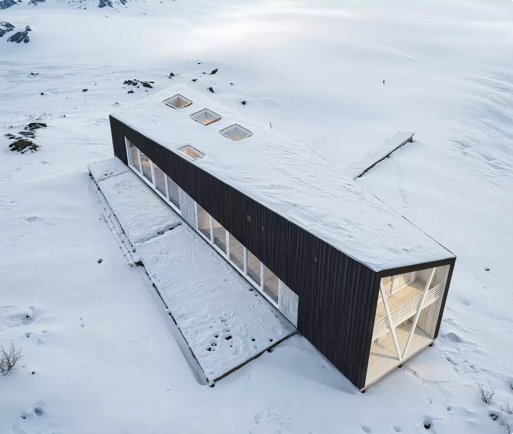 Winter classic rendering of a long black cabin with skylights in a snow-covered landscape