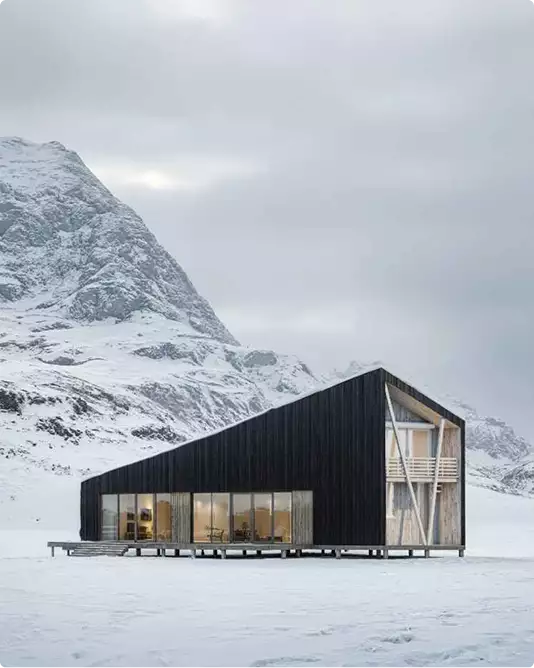 3D architectural exterior rendering for a black cabin on a snowy plain below mountains