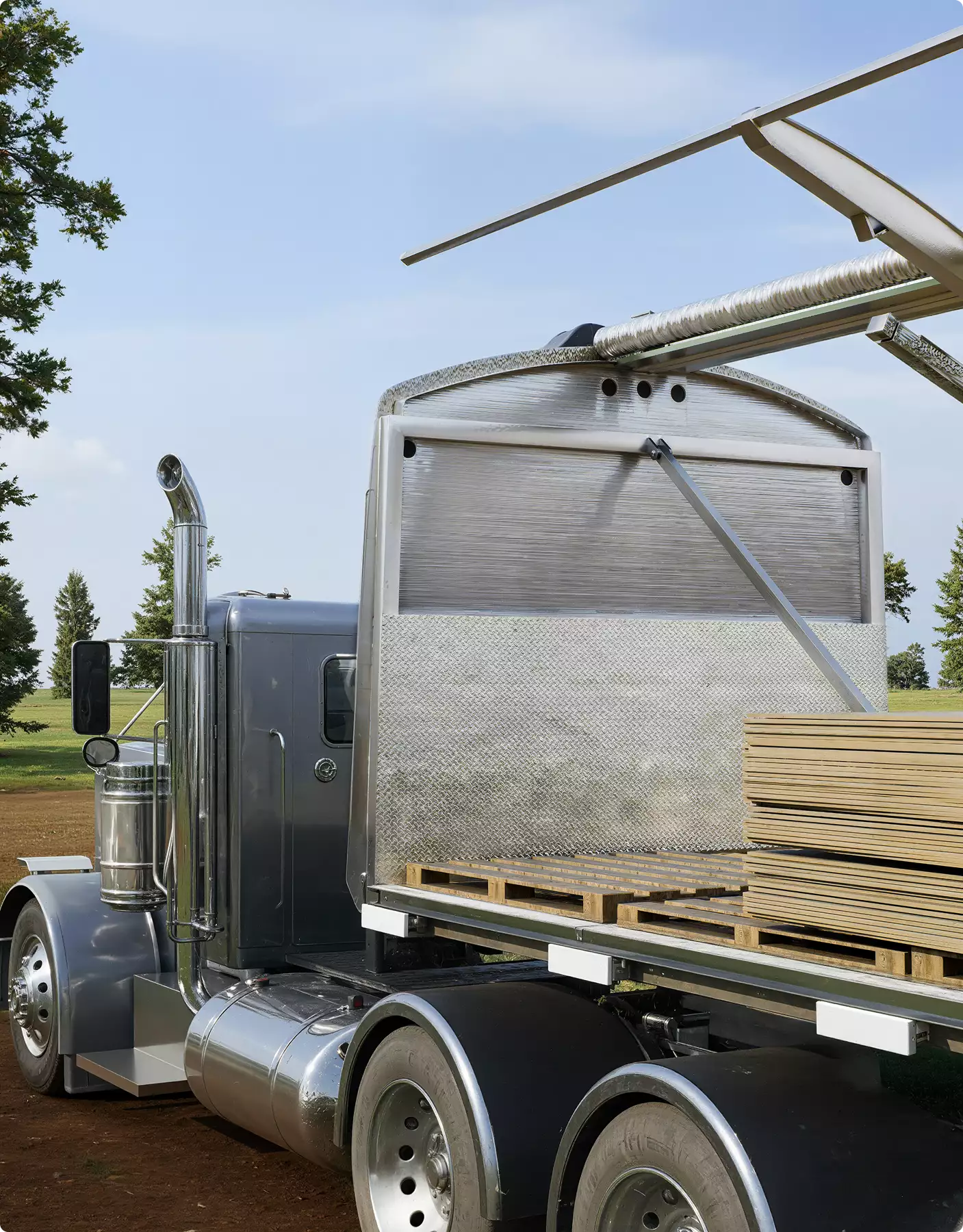 Flatbed truck carrying stacked wood panels outdoors, Automotive Rendering Service
