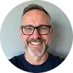 Clients portrait of man with glasses smiling, beard, indoor background, neutral lighting