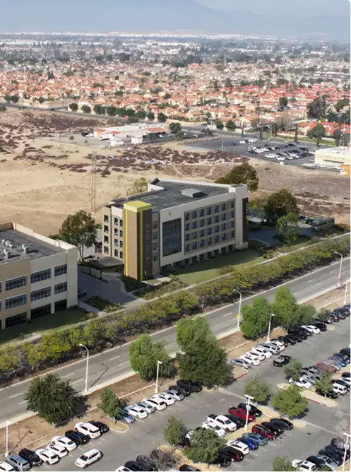 Exterior rendering services for a mid-rise commercial building beside a road and parking lots