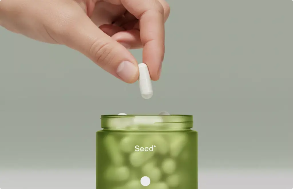 Hand holding capsule over green jar Product modeling supplement usage detail