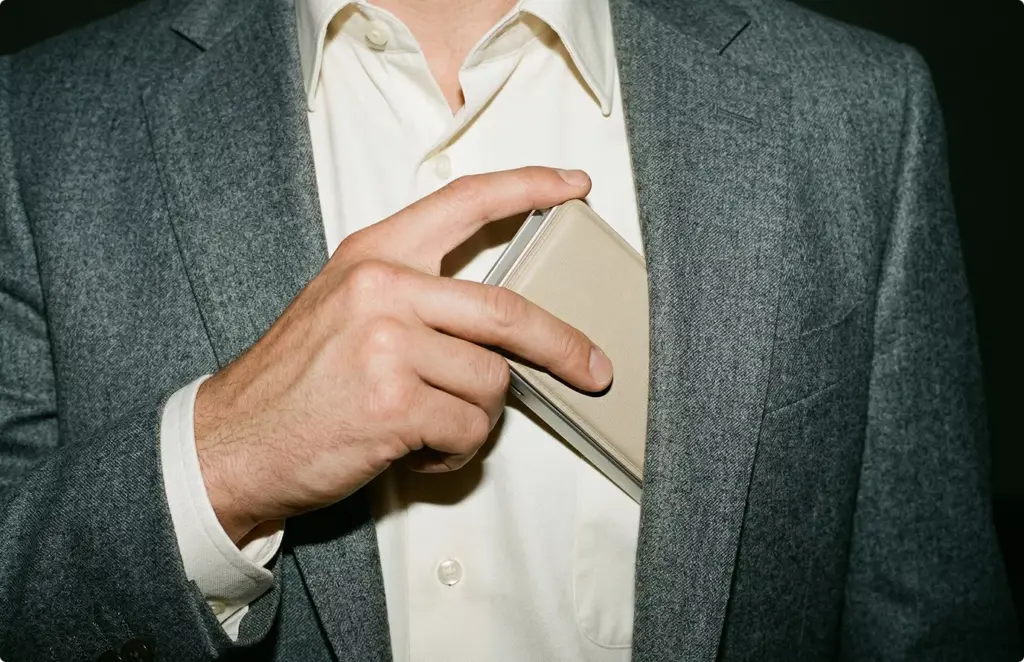 Man placing slim wallet into blazer pocket, product rendering lifestyle close-up