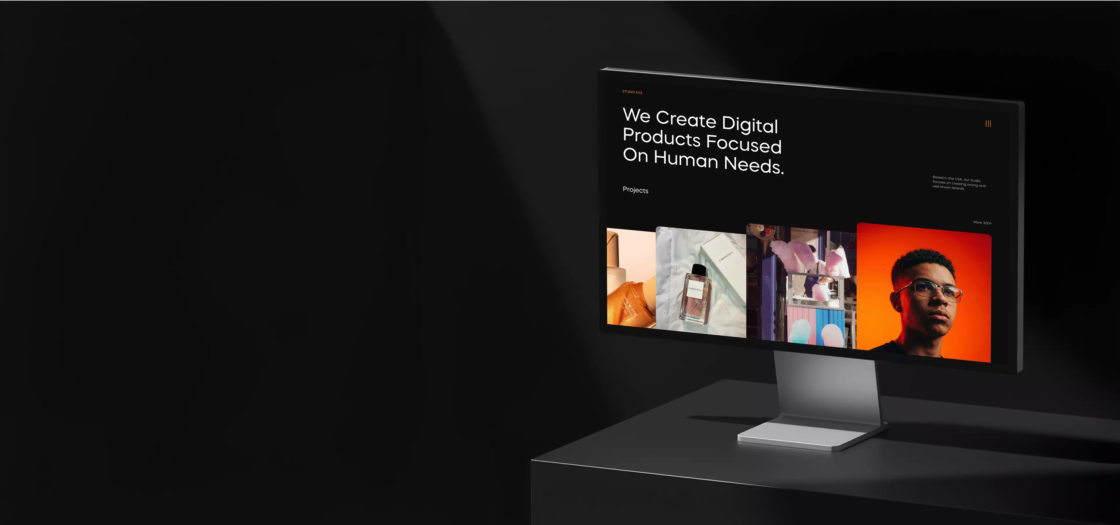 Desktop monitor displaying a web design portfolio on a dark studio desk
