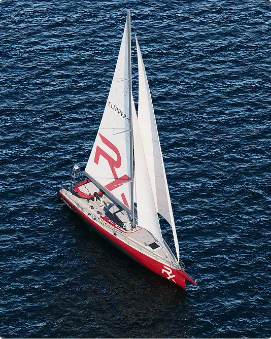Aerial sailing yacht rendering with red hull and white sails moving across deep blue sea