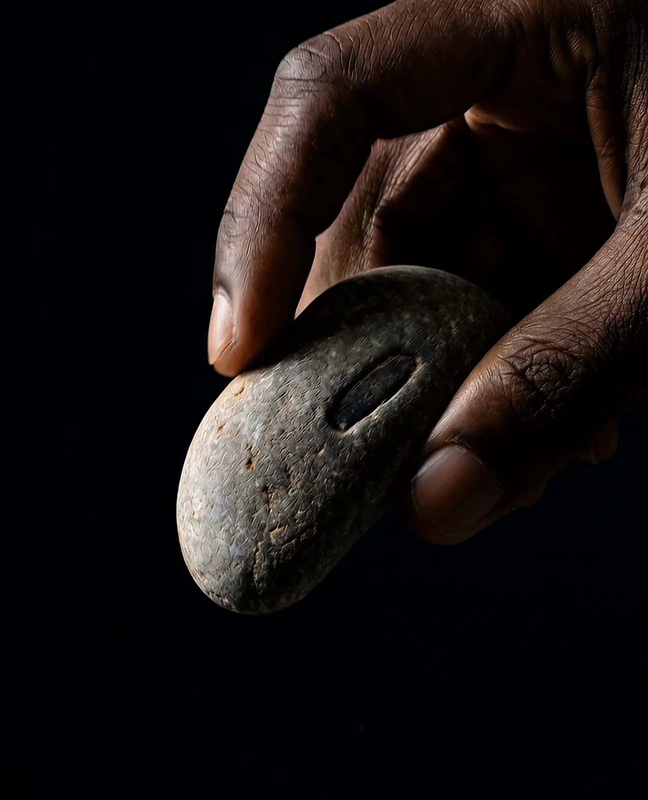 Hand holding a stone on a dark background, concept render.
