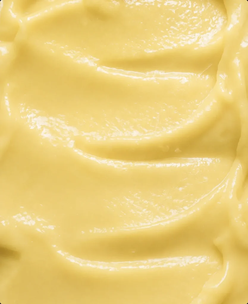 Macro close-up of glossy yellow face cream texture, AI product visualization detail.